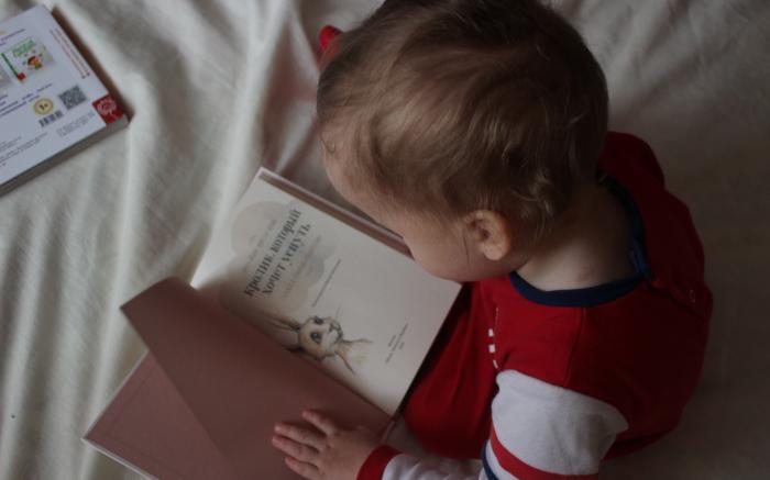 baby sitting on bed while reading on book by Iana Dmytrenko courtesy of Unsplash.