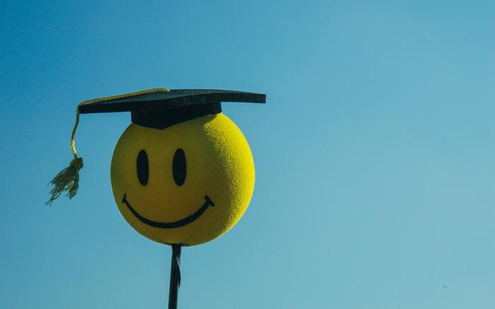 a smiley face wearing a graduation cap by Rohit Tandon courtesy of Unsplash.