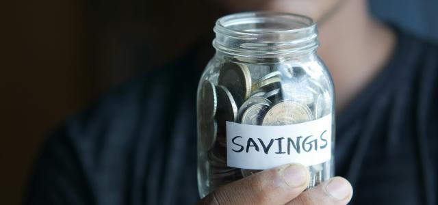 a man holding a jar with a savings label on it by Towfiqu barbhuiya courtesy of Unsplash.