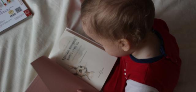 baby sitting on bed while reading on book by Iana Dmytrenko courtesy of Unsplash.