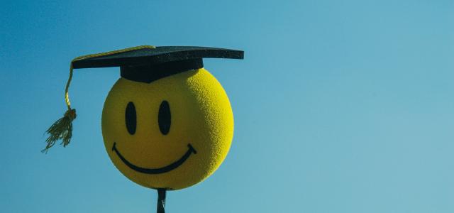a smiley face wearing a graduation cap by Rohit Tandon courtesy of Unsplash.